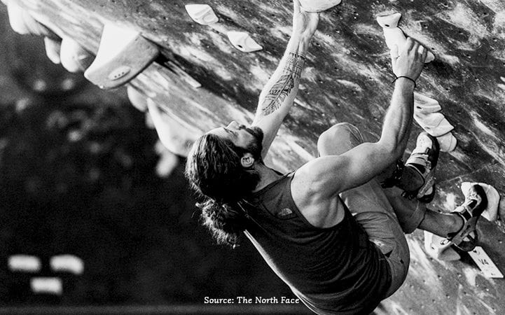 man rock climbing black and white
